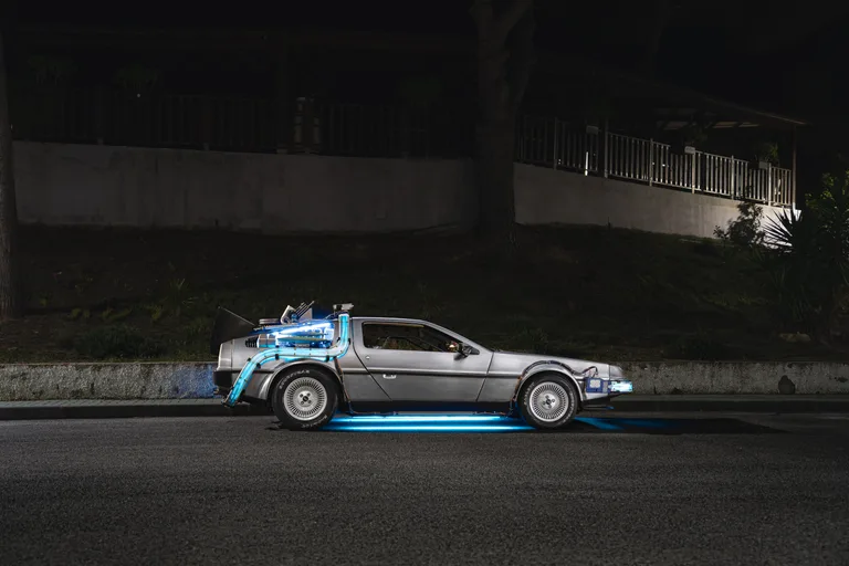 Side profile of the DeLorean Time Machine at night, gull-wing door hinge mechanism visible — for hire in Spain