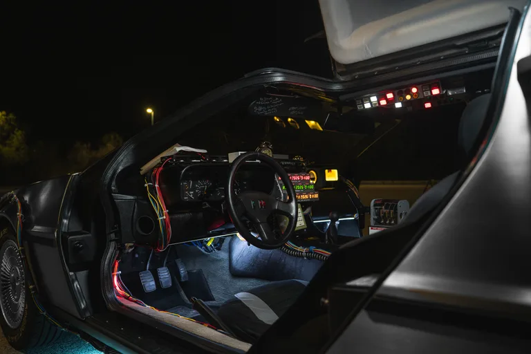 DeLorean Time Machine cockpit interior at night — steering wheel, time circuits and blue floor lighting