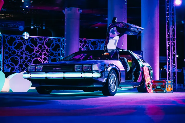 DeLorean Time Machine at a corporate event with purple stage lighting and DISCO backdrop — brand activation hire