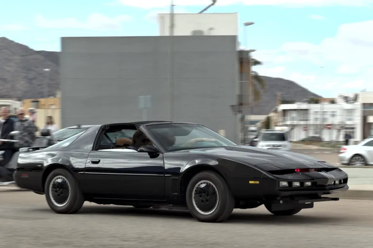 Rent KITT from Knight Rider — black Pontiac Firebird Trans Am, side profile on road with mountain backdrop