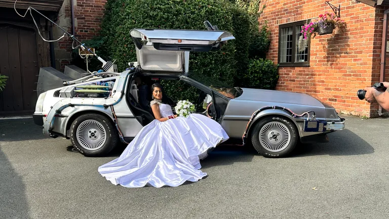 Quinceañera in a ball gown sitting in the open gull-wing of the DeLorean Time Machine — rent the DeLorean for quinceañeras