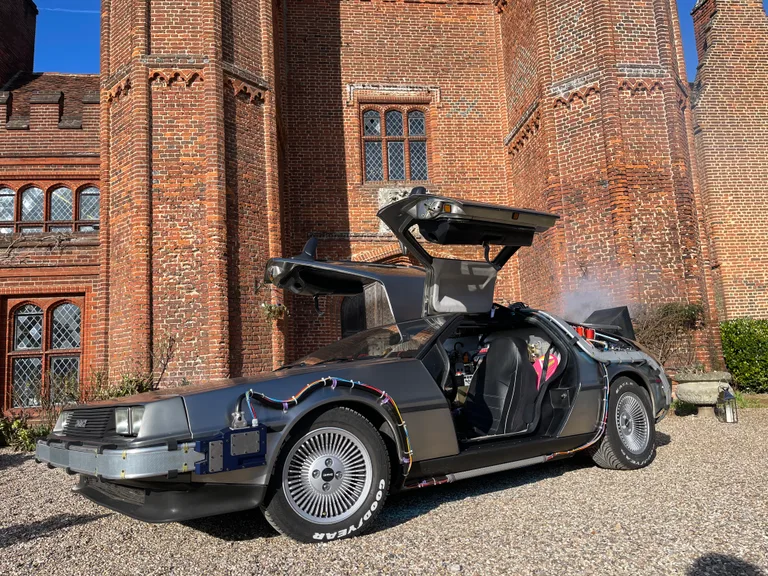 DeLorean Time Machine with both gull-wing doors raised parked in front of a manor house — wedding venue hire