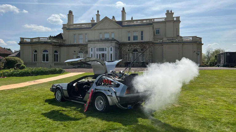 DeLorean Time Machine with gull-wing open and dry-ice smoke effect in front of a stately home — rent for weddings & events
